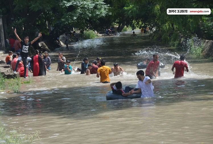भीषण गर्मी में नहर में आनंद लेते लोग