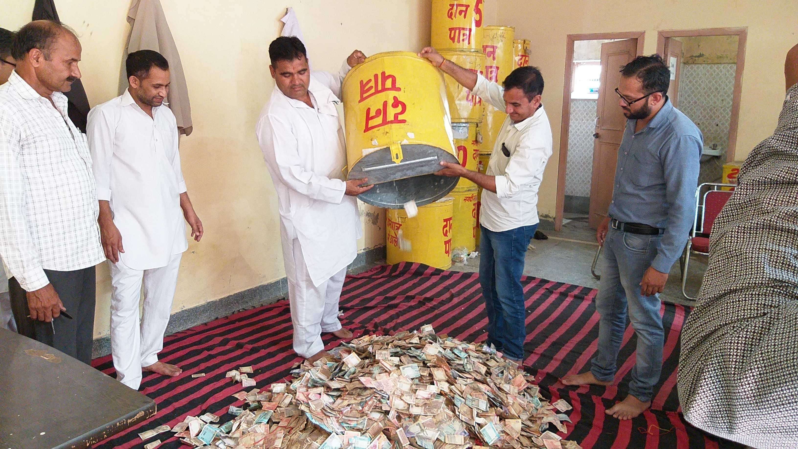 दानपात्र से राशि निकालते हुए कर्मचारी दानपात्र से राशि निकालते हुए कर्मचारी