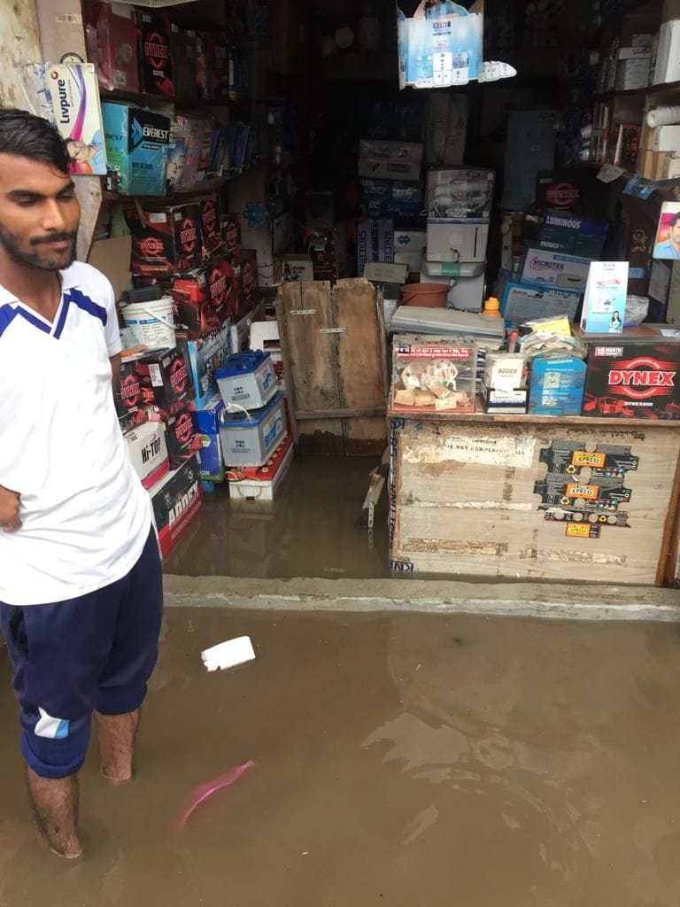 फोटो नंबर 12- सिंघाना रोड पर दुकानों के अंदर व बाहर जमा बरसाती पानी।