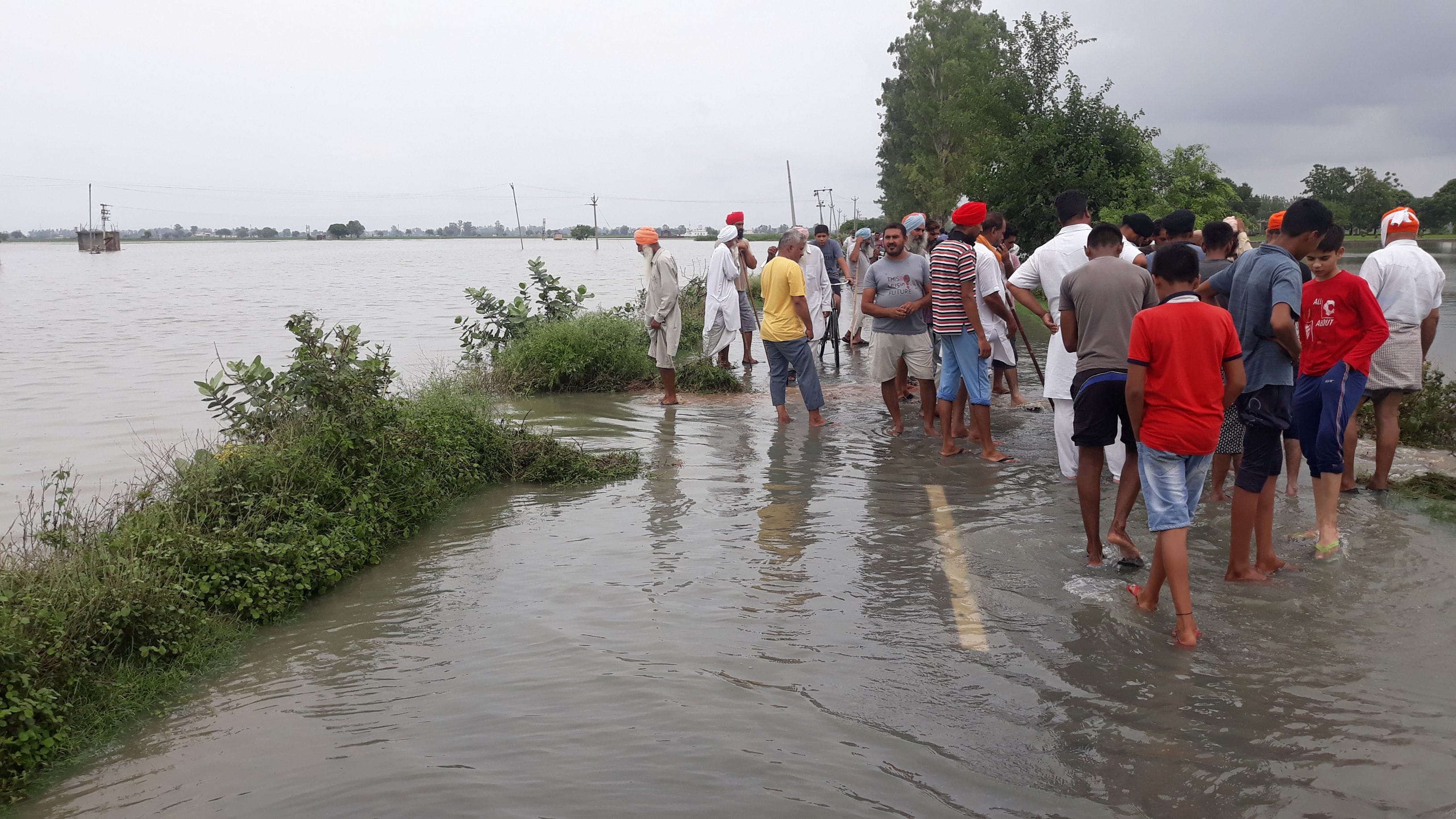 गांव घमुर खेडी में खेतों में घुसा बारिश का पानी सड़क पर खडे ग्रामीण ।