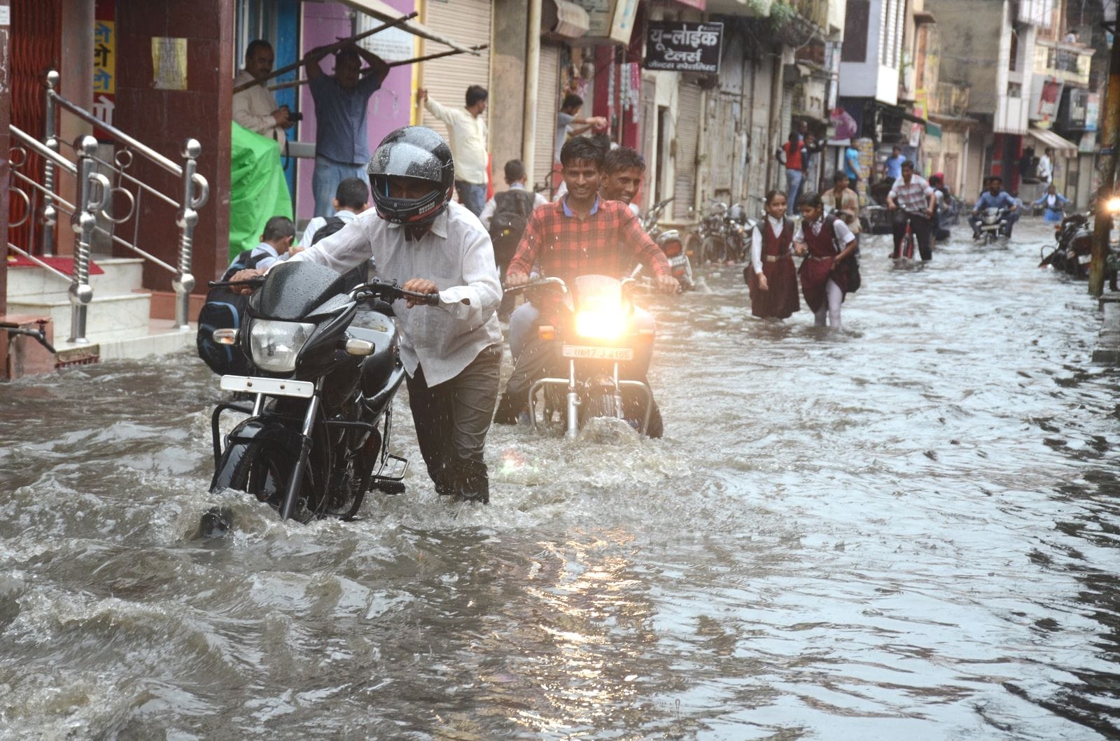 रुड़की में दोपहर से समय हुई तेज बारिश के कारण अंबर तालाब में हुए जलभराव के बीच से गुजरते लोग।