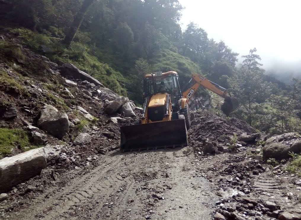 बागेश्वर के कपकोट क्षेत्र में सड़क से मलबा हटाती जेसीबी।