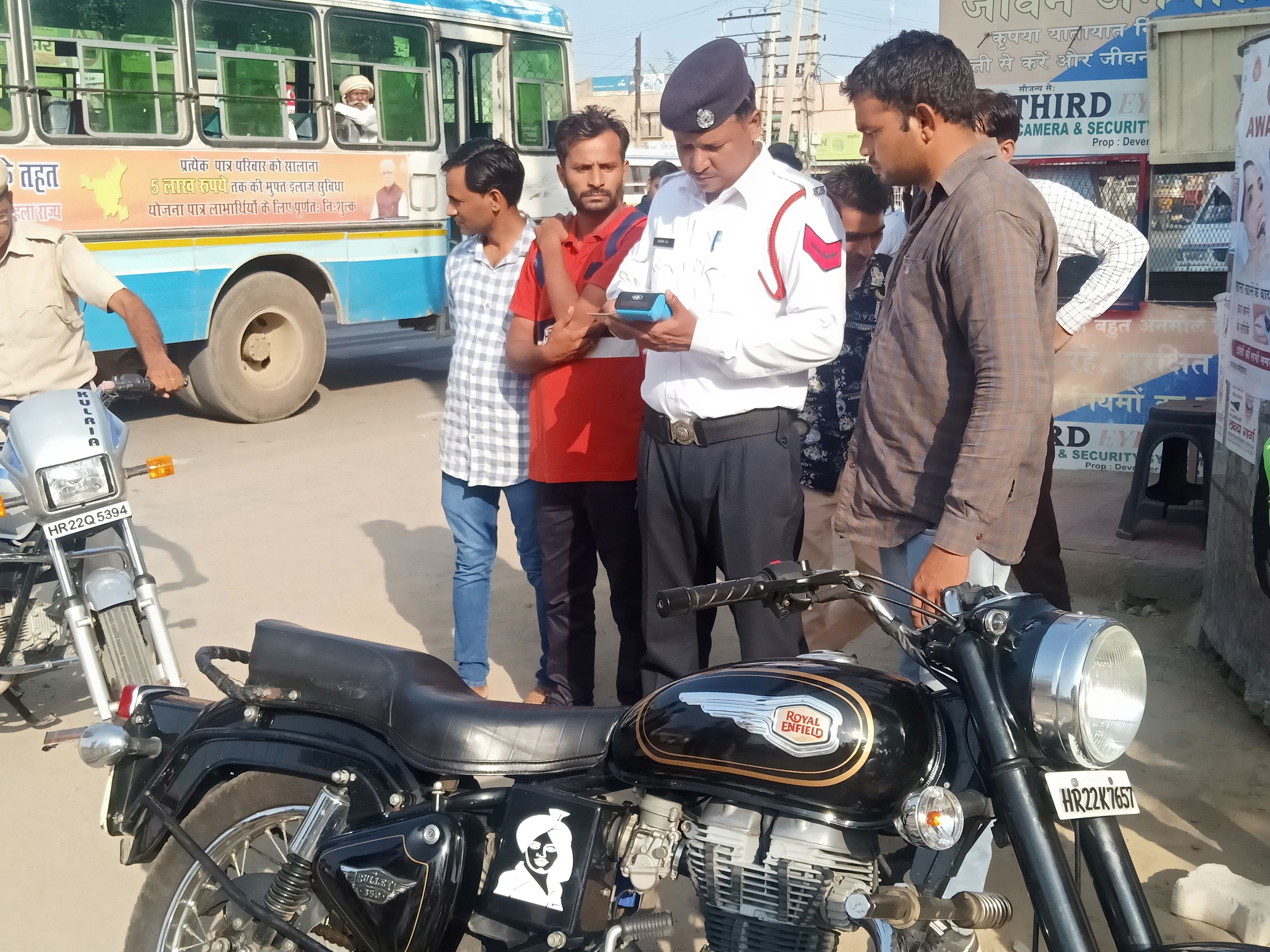 बुलेट बाइक सवार का चालान काटते ट्रैफिक पुलिसकर्मी ।