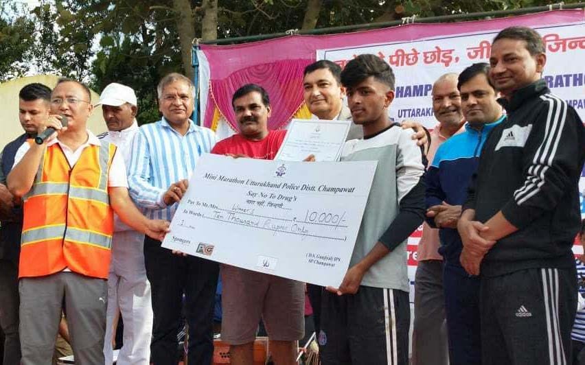 नशे के खिलाफ निकाली गई मिनी मैराथन दौड़ के चंपावत के विजेता मनीष बिष्ट को चेक देते जिला जल आशीष नै? नशे के खिलाफ निकाली गई मिनी मैराथन दौड़ के चंपावत के विजेता मनीष बिष्ट को चेक देते जिला जल आशीष नै?