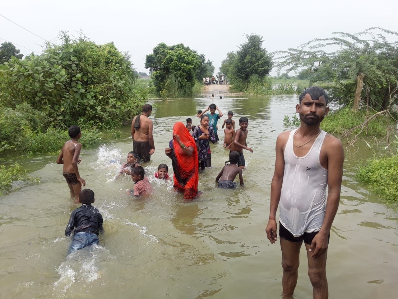 कुठौंद में भरे पानी के बीच निकलते लोग