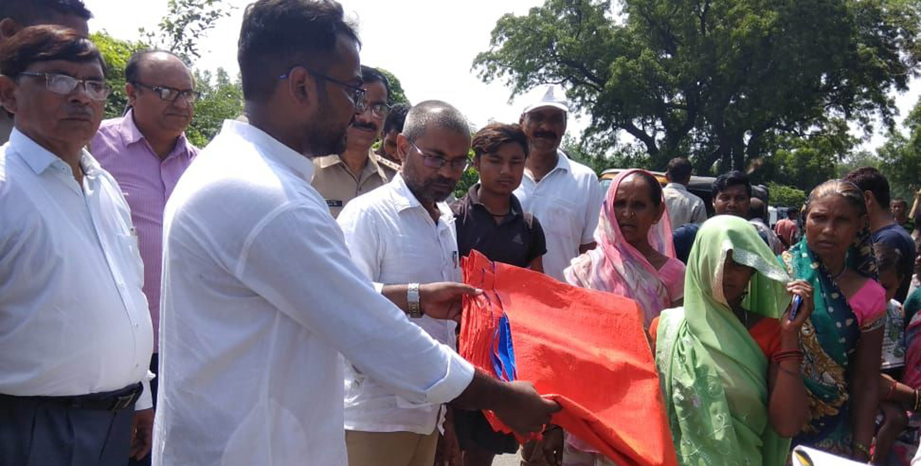 बाढ़ पीड़ितों को पॉलिथिन देते विधायक बृजेश प्रजापति।