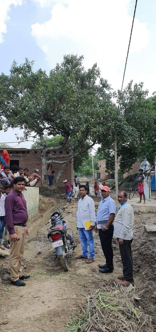 बाढ़ का पानी उतरने के बाद रास्ते में मिट्टी डालते मजदूर