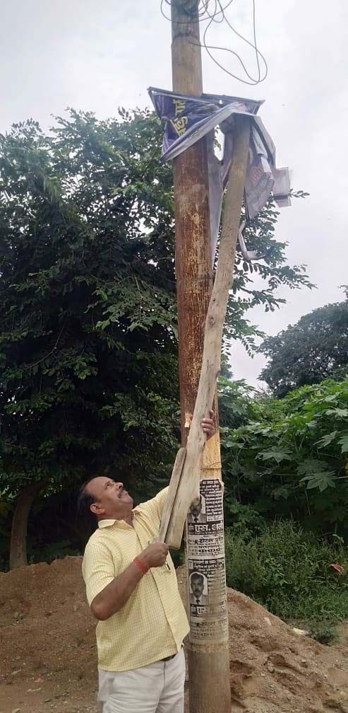 सदर ब्लाक के सगरा गांव में लगी राजनीतिक होर्डिग्स को पोल से उतारता लेखपाल।