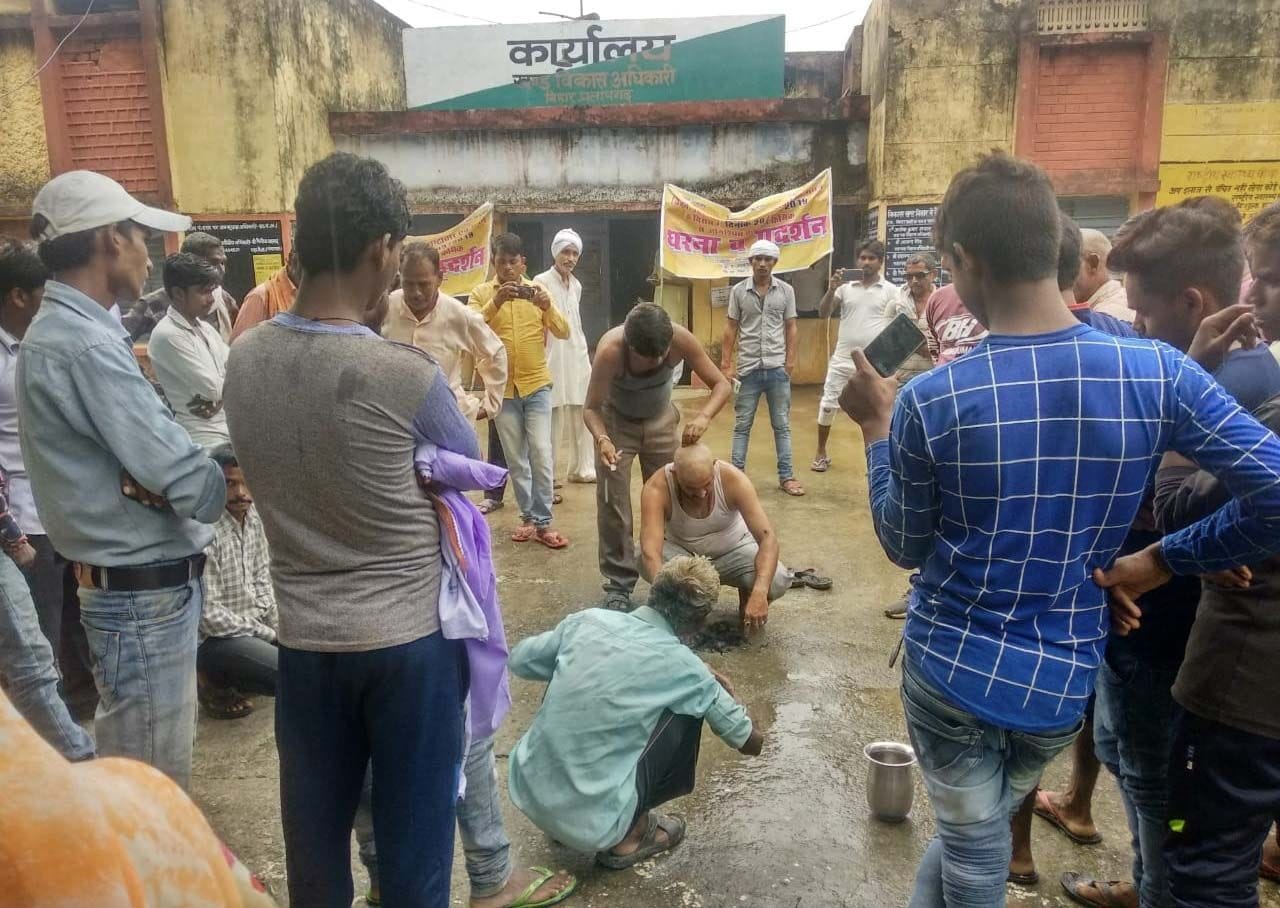 हिार ब्लाक में भ्रष्टाचार के विरोध में मुंडन कराते मलावा छजईपुर के लोग।