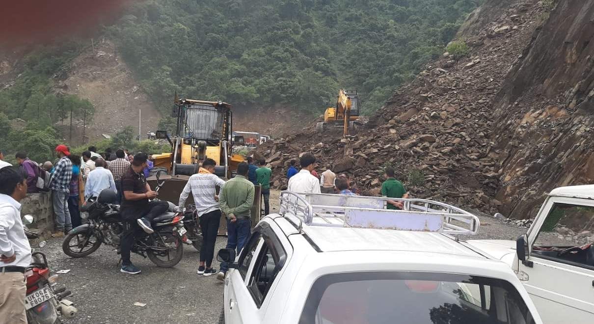 चंपावत जिले के स्वांला में एनएच में आए मलबे ने रोकी यात्रियों की राह।