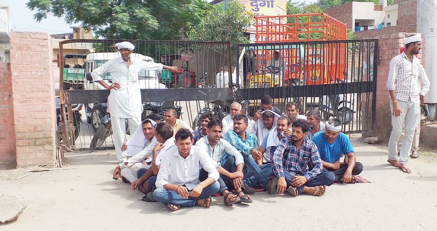 धान की खरीद नहीं होने से मंडी के गेट पर ताला लगाकर धरने पर बैठे किसान।