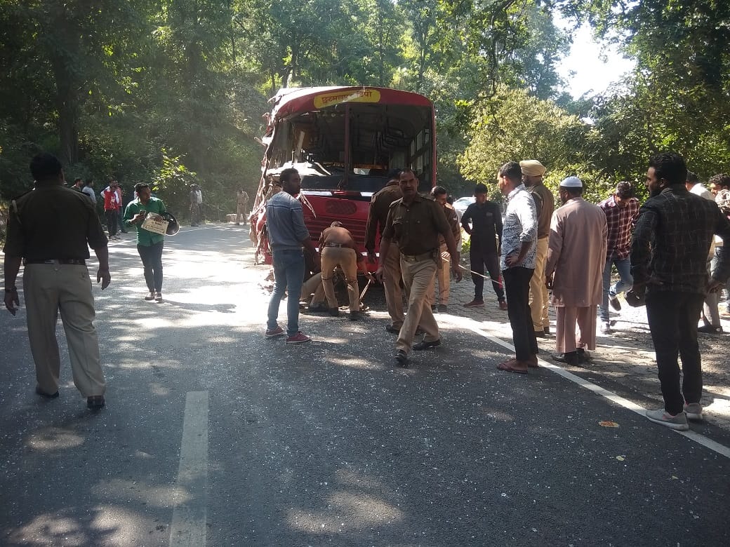 बिहारीगढ़ के दून हाईवे पर हादसे के बाद क्षतिग्रस्त बस और सवारियां