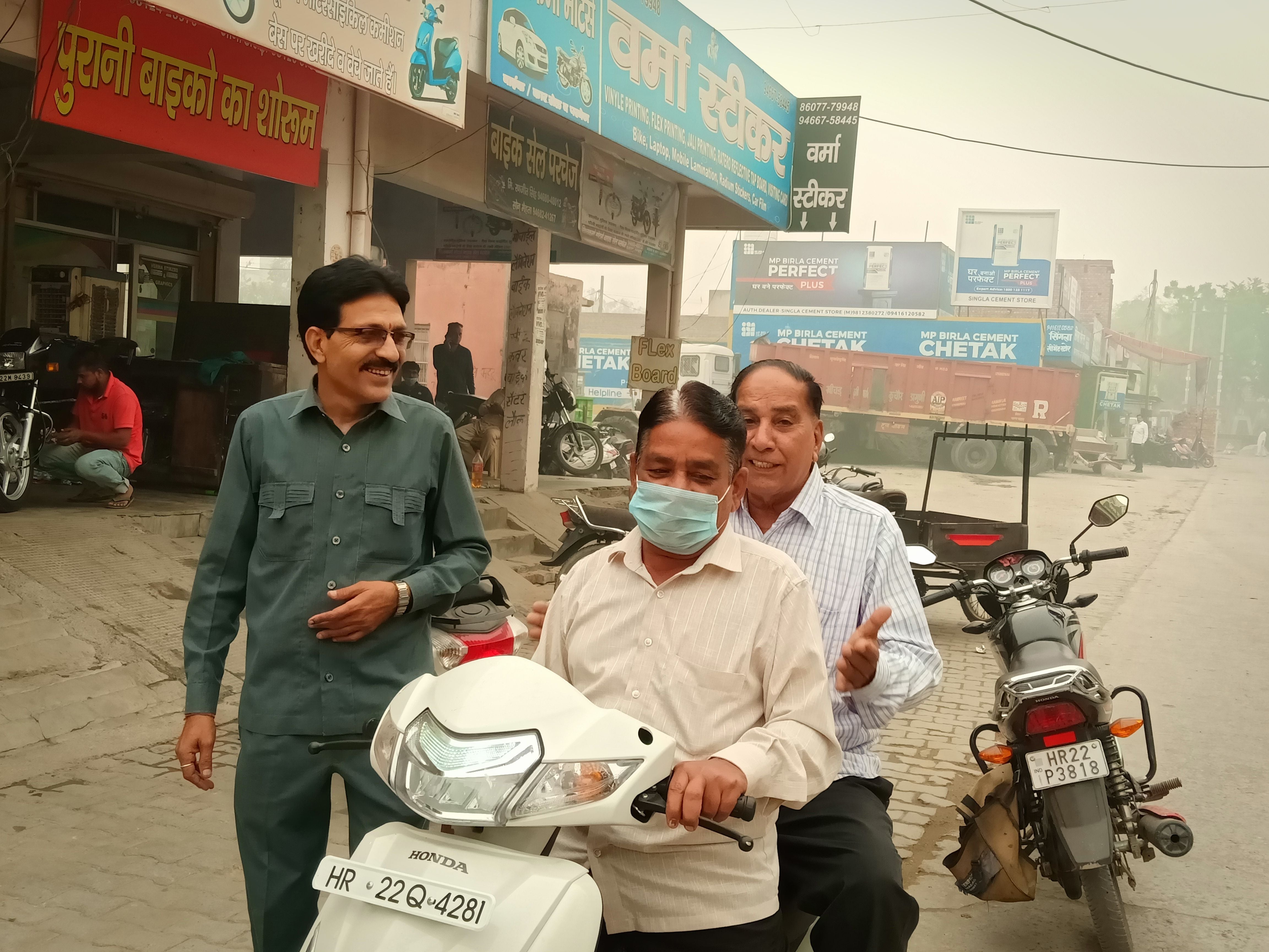 मुंह में मास्क पहनकर सड़क से होकर जाते स्कूटी सवार।
