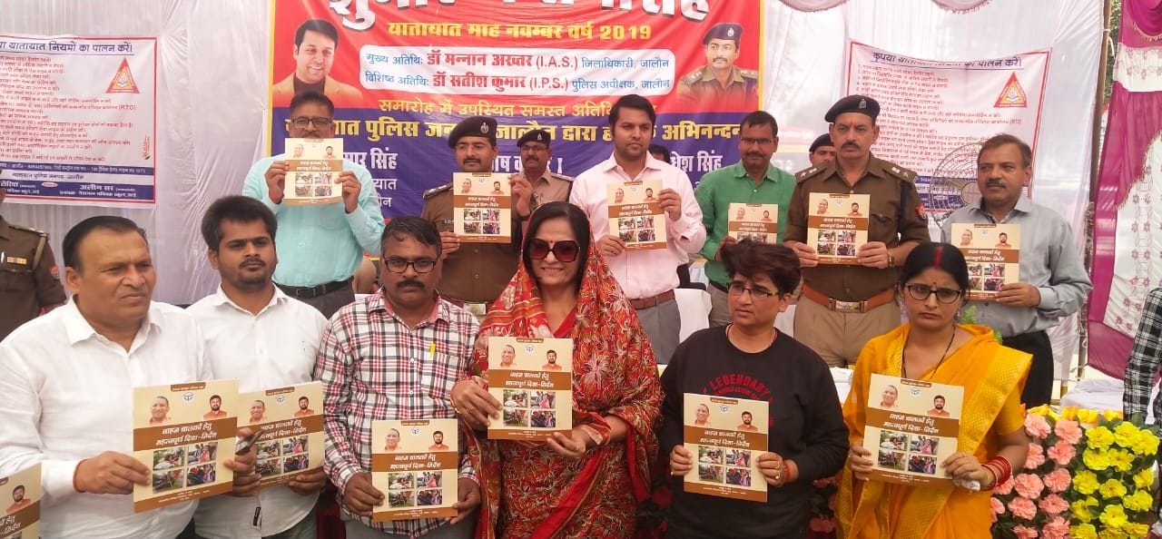 यातायात माह में यातायात  के नियमों की पुस्तकें दिखाते अधिकारी व समाजसेवी