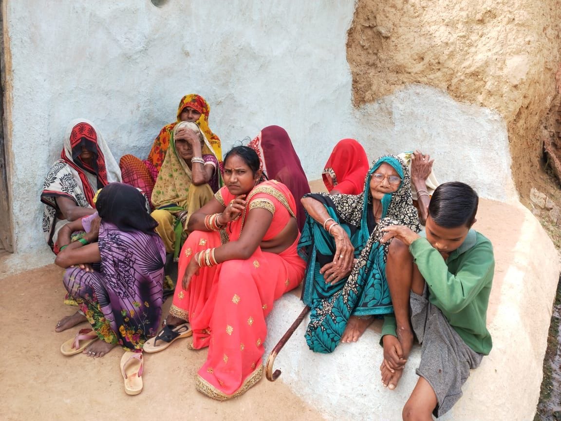 महिला के घर के बाहर बैठीं महिलाएं। महिला के घर के बाहर बैठीं महिलाएं।
