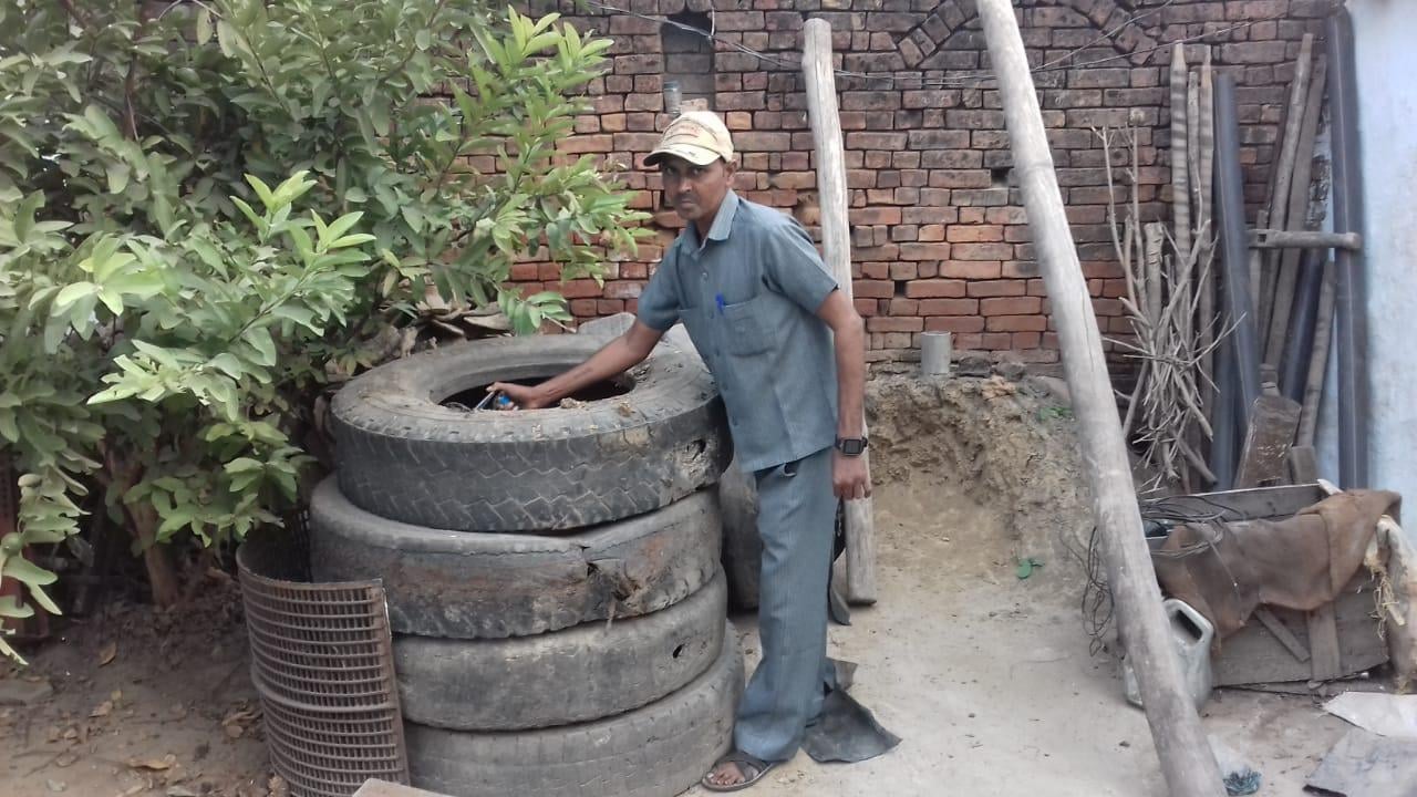 खराब पड़े टायरों में दवा छिड़काव करता कर्मचारी