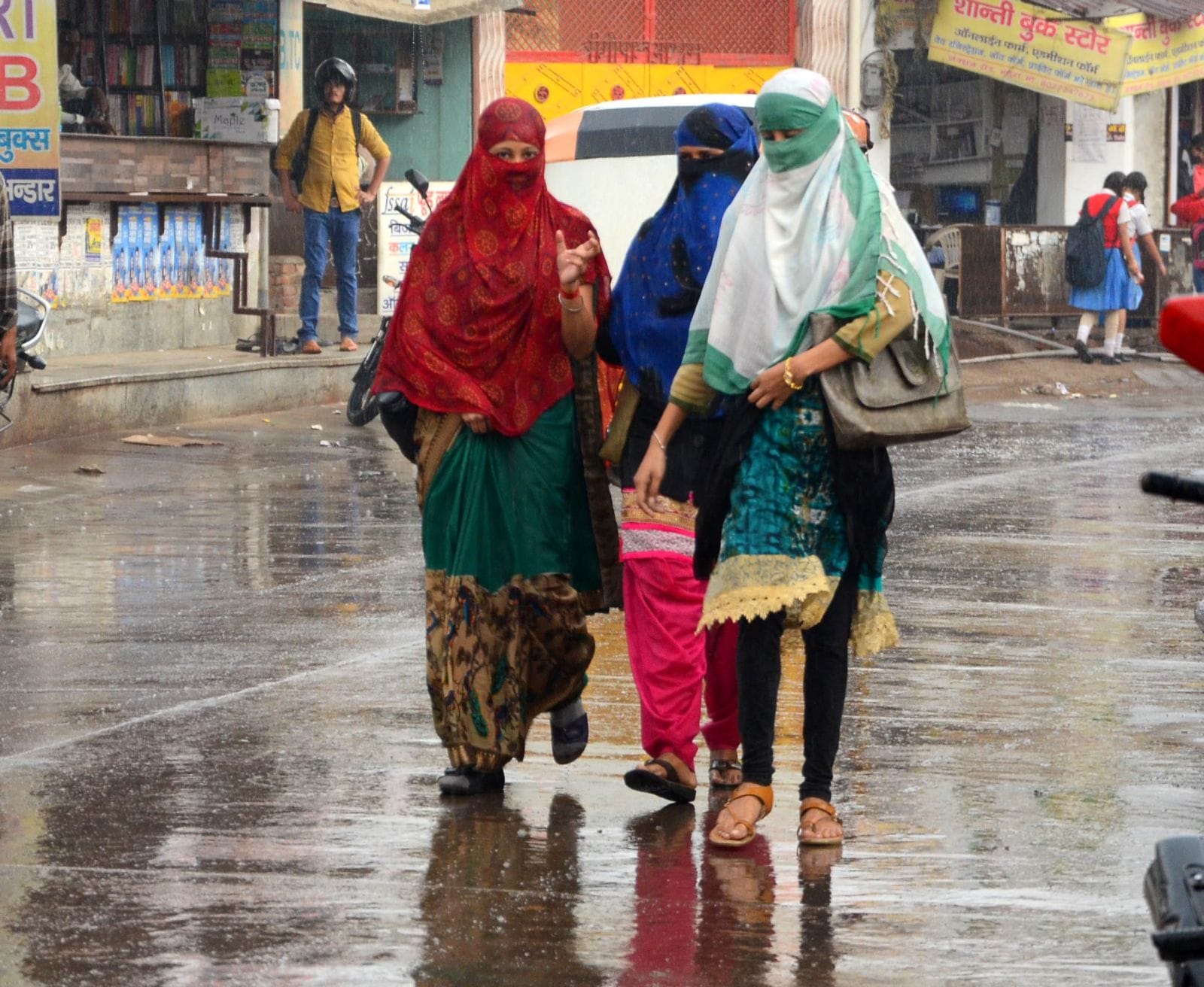 फोटो 52आर मौसम में आये बदलाव से हुई बारिश में भीगकर जाती युवतियां।