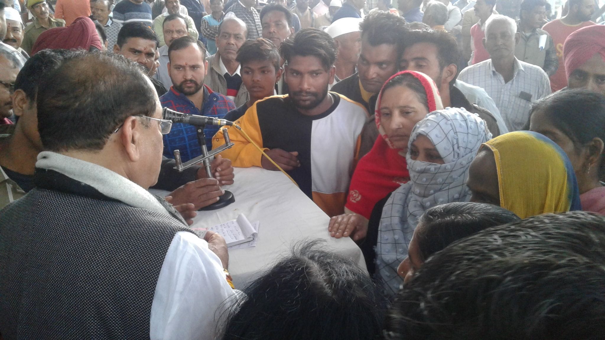 बाजपुर चीनी मिल पेराई सत्र शुभारंभ के दौरान कैबिनेट मंत्री आर्य को घेरते मृत आश्रित।