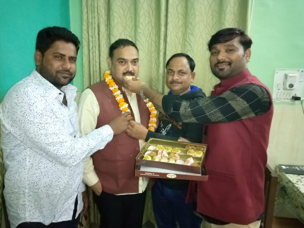 मिठाई खिलाते कार्यकर्ता।