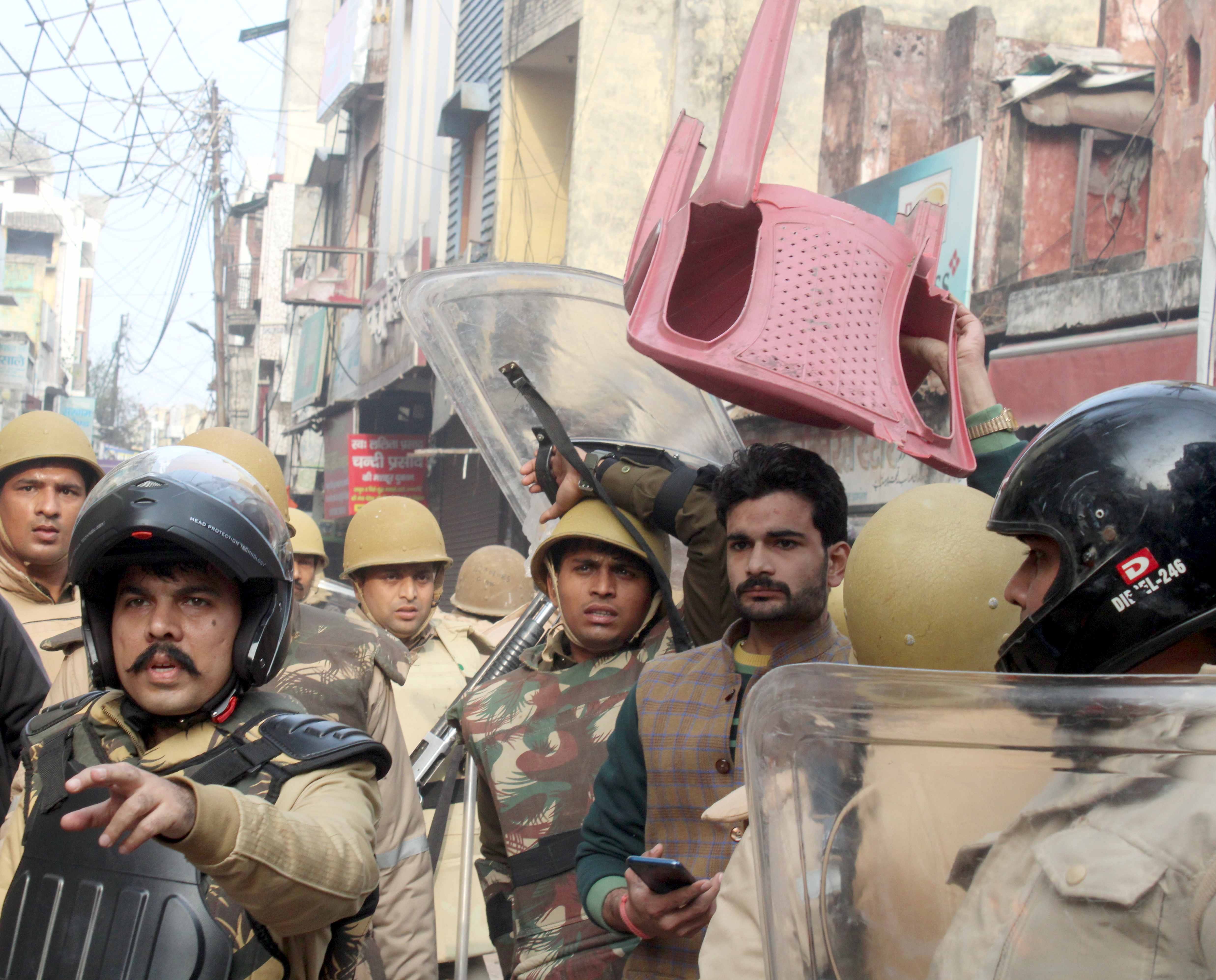 अमरोहा के मोहल्ला कोट में पथराव-आगजनी के दौरान सिर पर कुर्सी रखकर खुद को बचाता युवक।