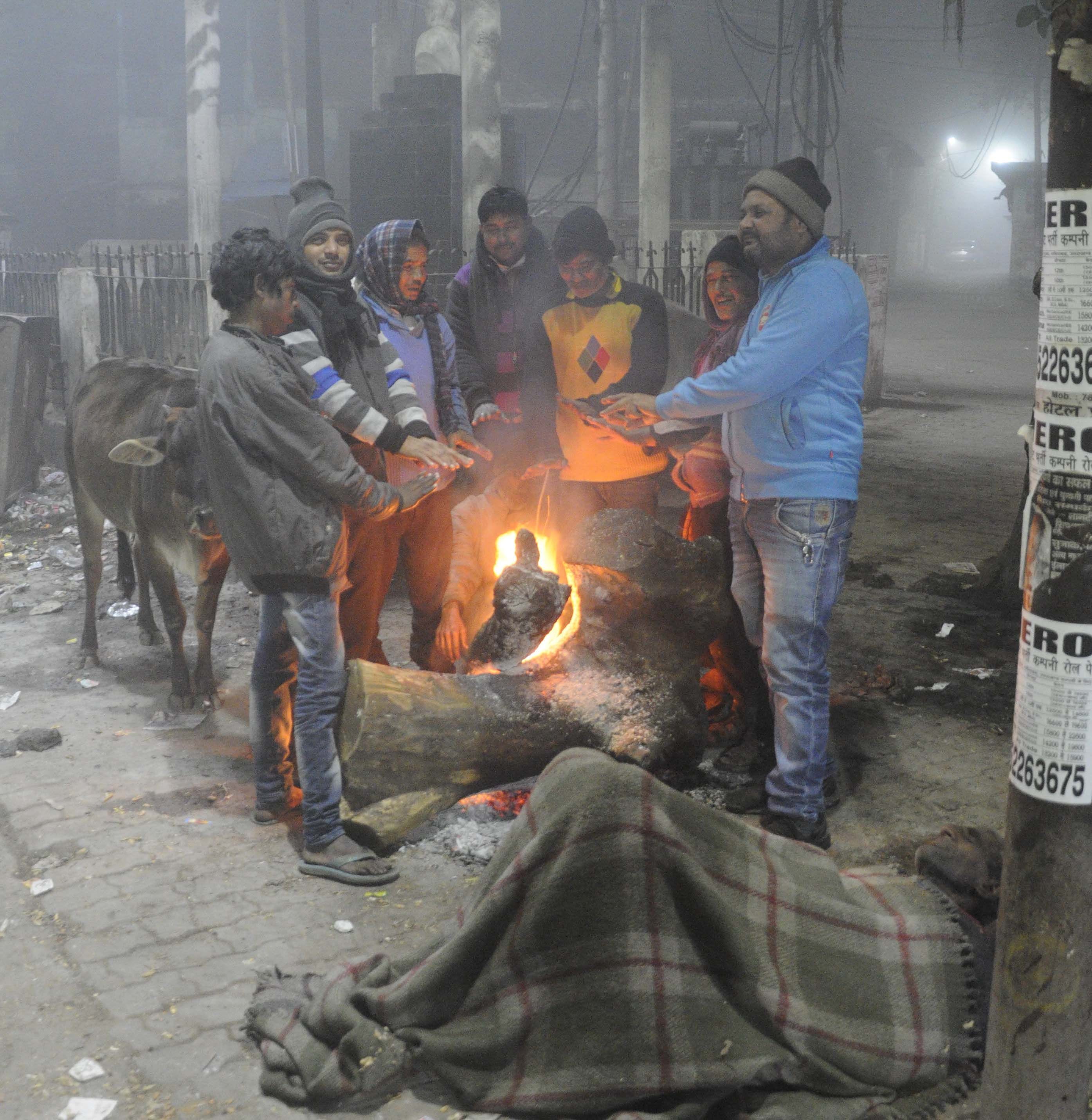 रेलवे स्टेशन तिराहे पर रात में अलाव के बगल जमीन पर सो रहा युवक व खड़े लोग। रेलवे स्टेशन तिराहे पर रात में अलाव के बगल जमीन पर सो रहा युवक व खड़े लोग।