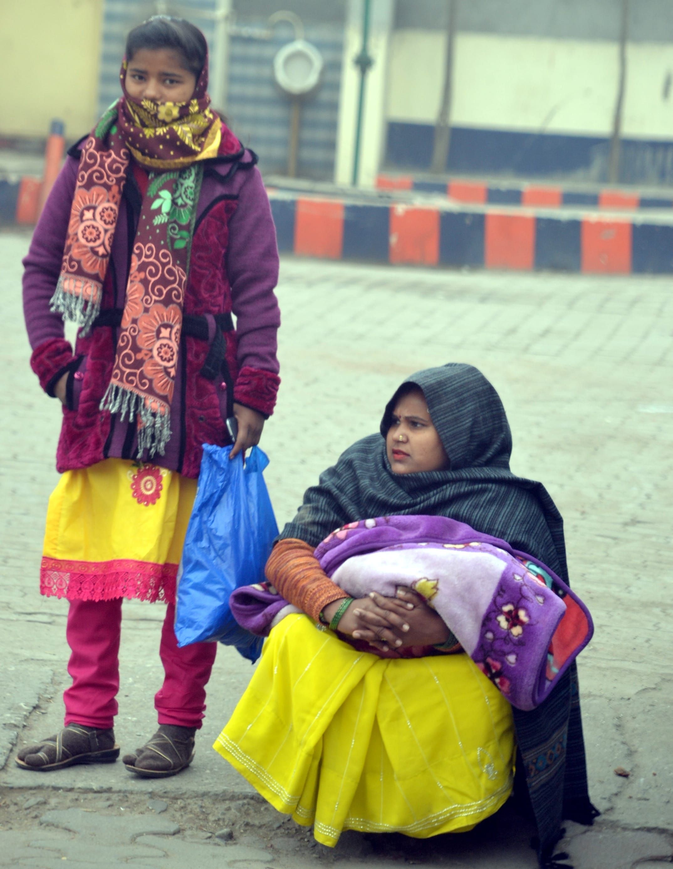 शामली सर्दी में बस अडडे पर कपडा लपेट कर बैठी महिला व युवती शामली सर्दी में बस अडडे पर कपडा लपेट कर बैठी महिला व युवती