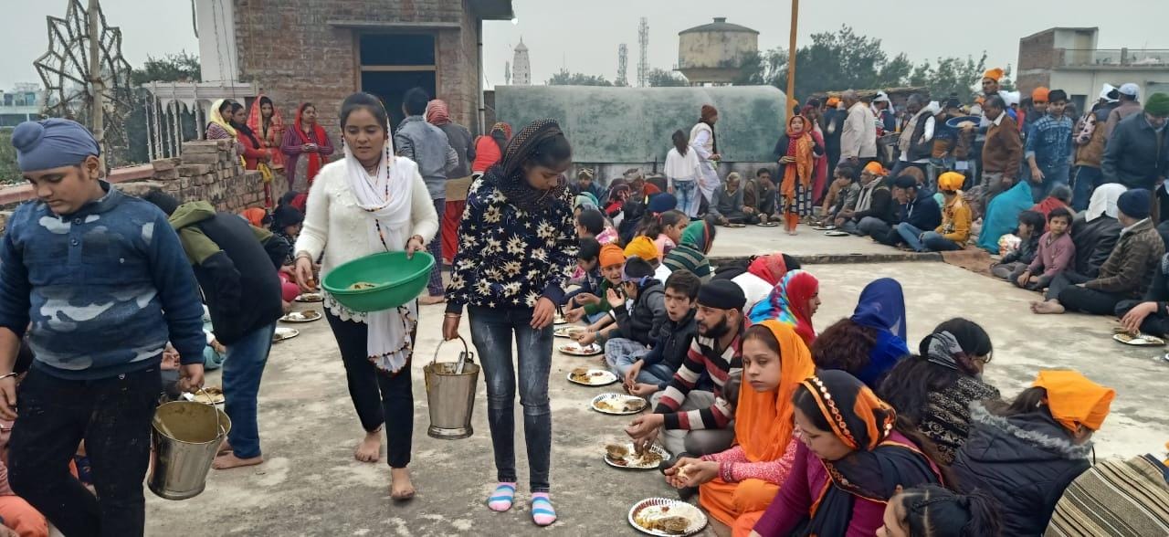 गुरुद्वारे में लंगर छकते लोग