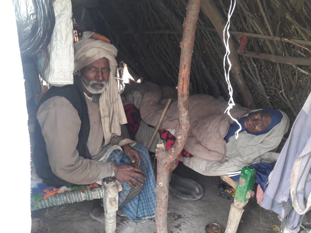 मोहम्मदाबाद क्षेत्र के खेत में मड़ैया में रजाई गद्दा डाल कर लेटे किसान हरचटी अहिरबार