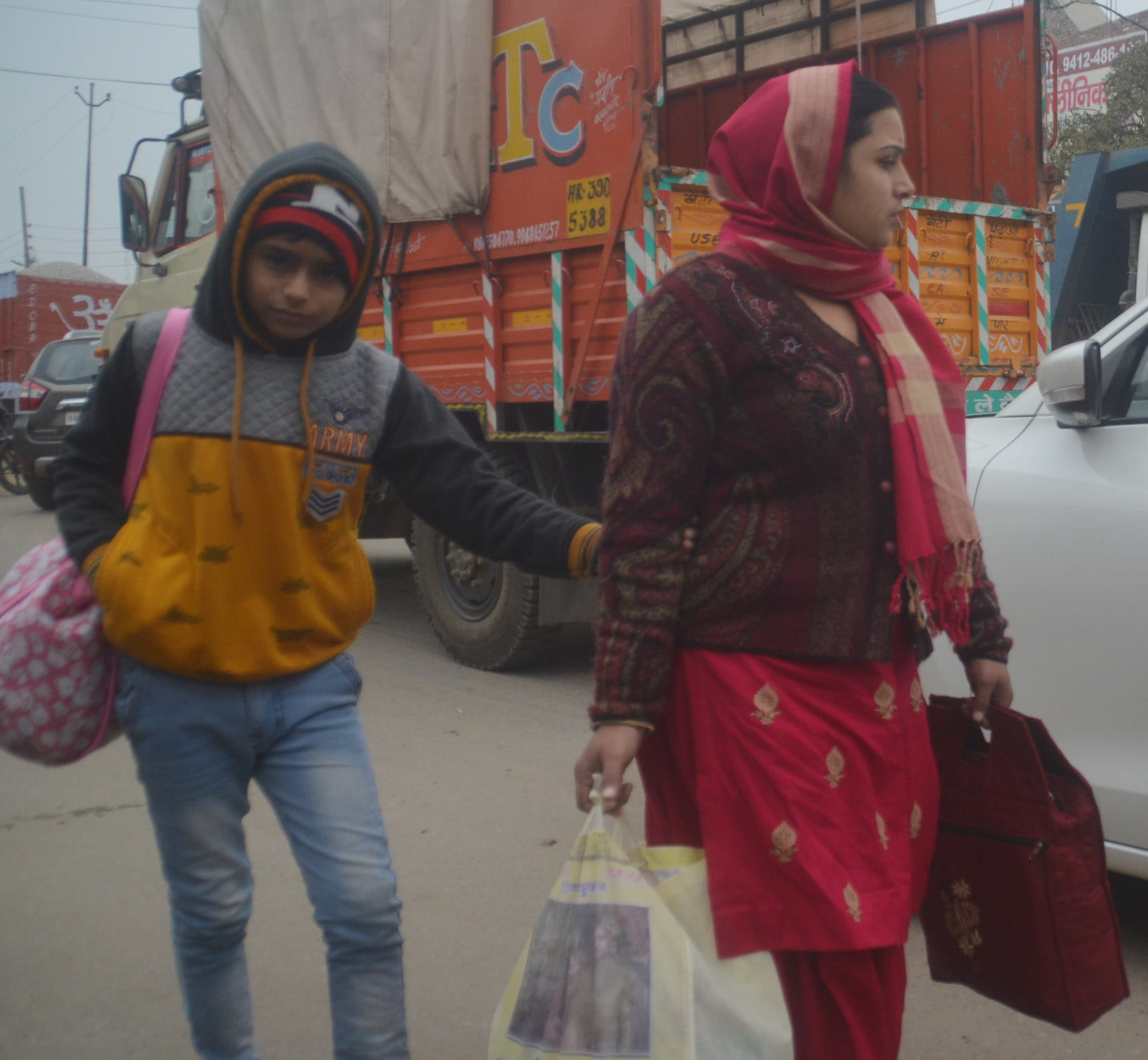 बागपत में बच्चे को गर्म कपड़े पहनाकर ले जाती महिला