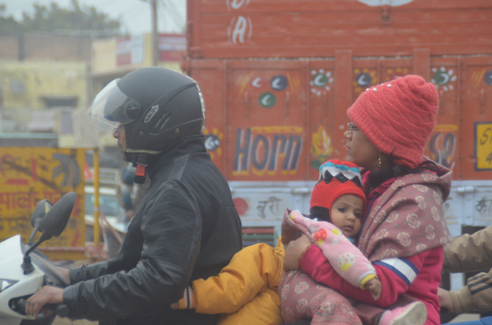 बागपत में सर्द हवा के बीच परिवार को गर्म कपड़े पहनाकर ले जाता युवक