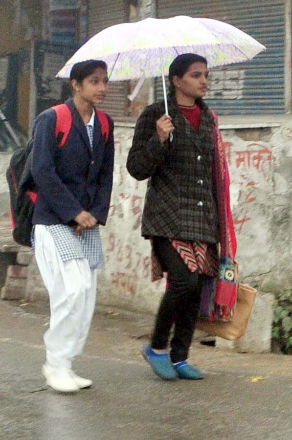 शामली बरसात के दोरान छाता लगा कर जाती युवतियां