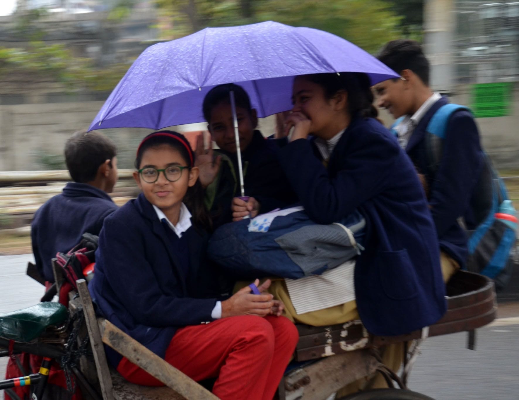  बारिश में स्कूल से छुट्टी के बाद छाता लगाकर जाते बच्चे।