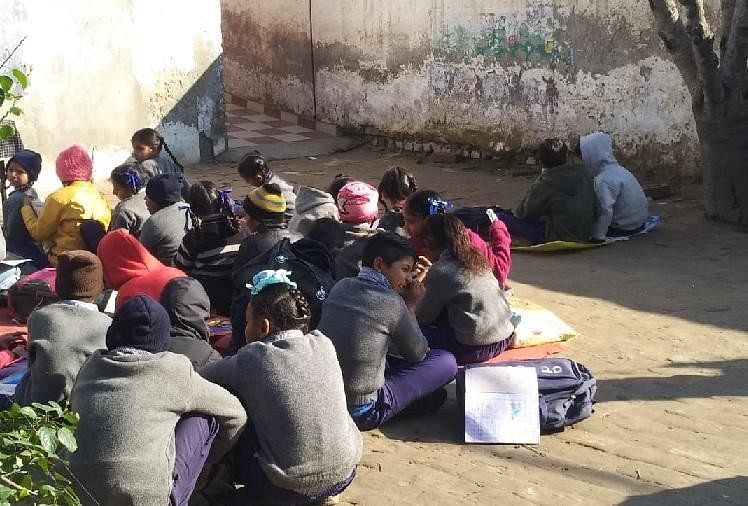 नीचे बैठकर पढ़ाई करते स्कूली बच्चे