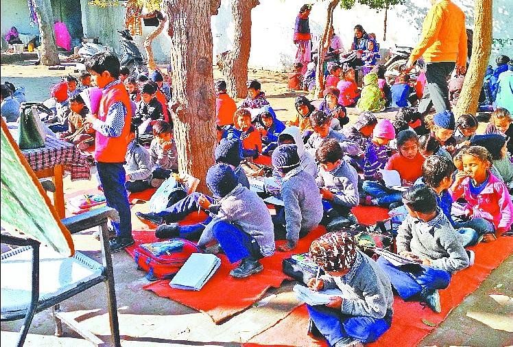 नीचे बैठकर पढ़ाई करते स्कूली बच्चे