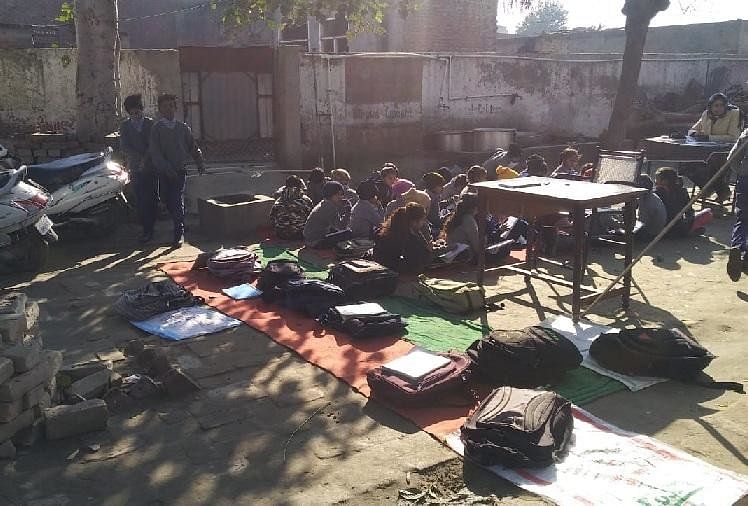 नीचे बैठकर पढ़ाई करते स्कूली बच्चे
