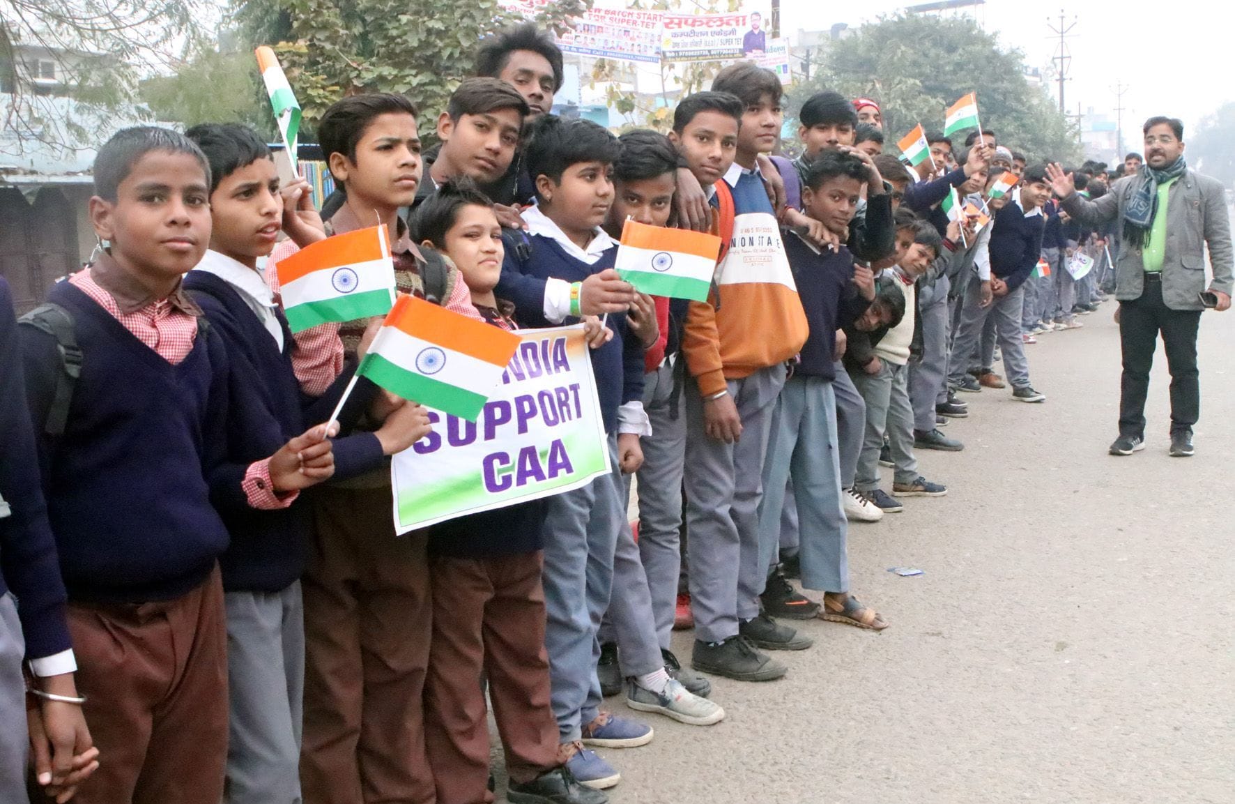 नागरिकता कानून के समर्थन में आगरा रोड पर मानव श्रृंखला बनाते स्कूल के बच्चे।