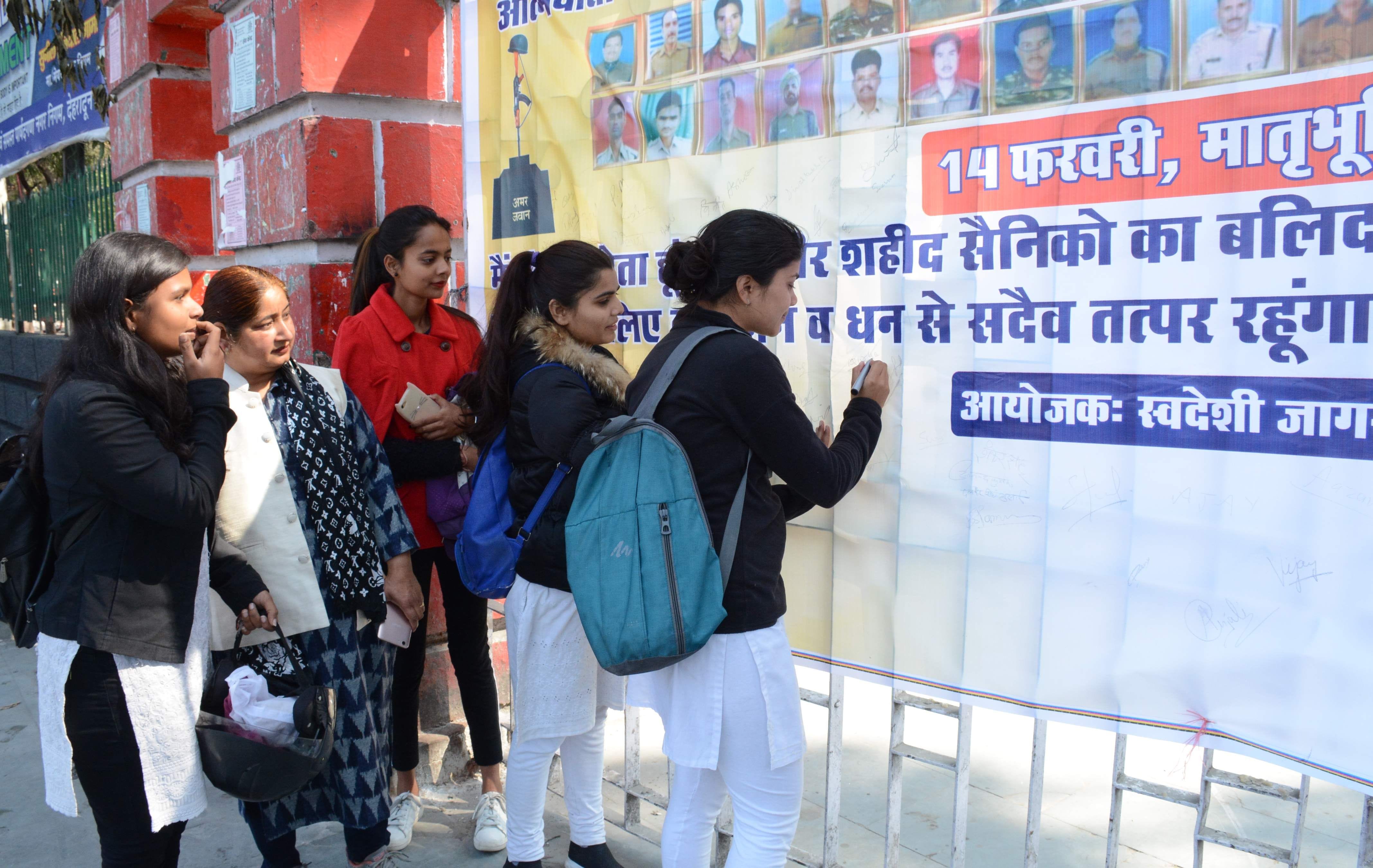 गांघी पार्क में पुलवामा के शहीद जवानों को श्रद्धांजलि देने के बाद हस्ताक्षर करती छात्राएं और मह?