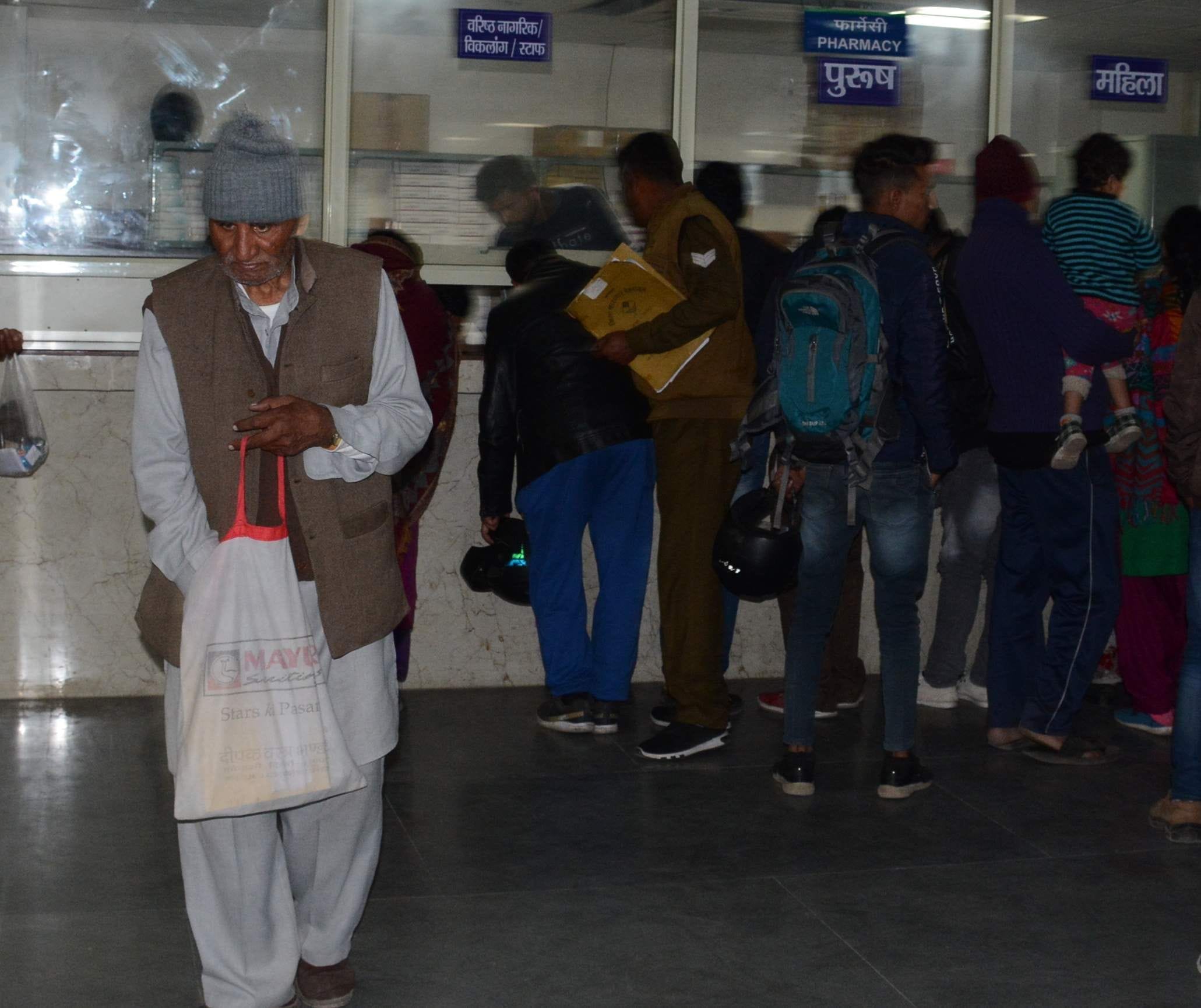 घंटो लाइन में लगे रहने के बाद दवाई लेकर जाते बुजुर्ग । 