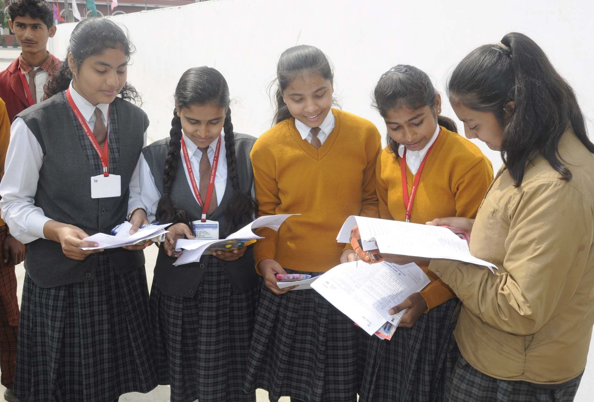 एंजिल्स इंटर कालेज में सीबीएसई बोर्ड की परीक्षा देकर बाहर निकली छात्राएं प्रश्न पत्रों को मिलात