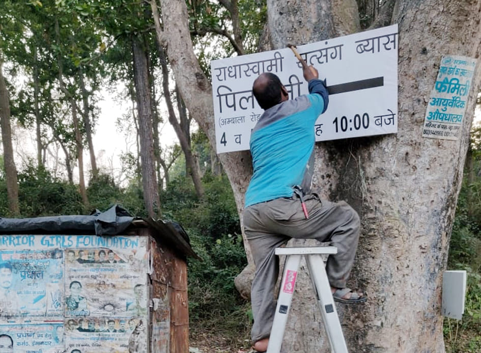 शहर में राधा स्वामी सत्संग के स्थहल मार्ग का बोर्ड लगाते कर्मी