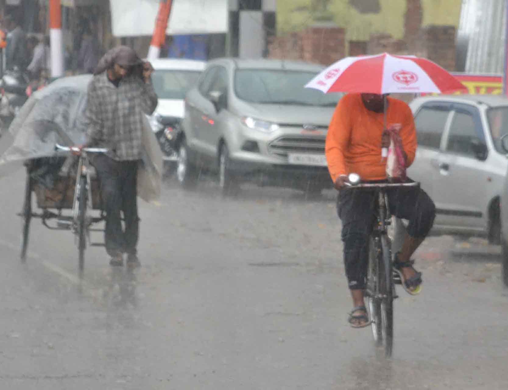 शामली बरसात में छाता लगा कर साईकिल पर गुजरता युवक शामली बरसात में छाता लगा कर साईकिल पर गुजरता युवक