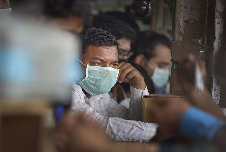 नई दिल्ली के सफदरजंग अस्पताल के बाहर एक दवा की दुकान पर कोरोनावायरस से बचाव के लिए मास्क पहने हुए लोग।
