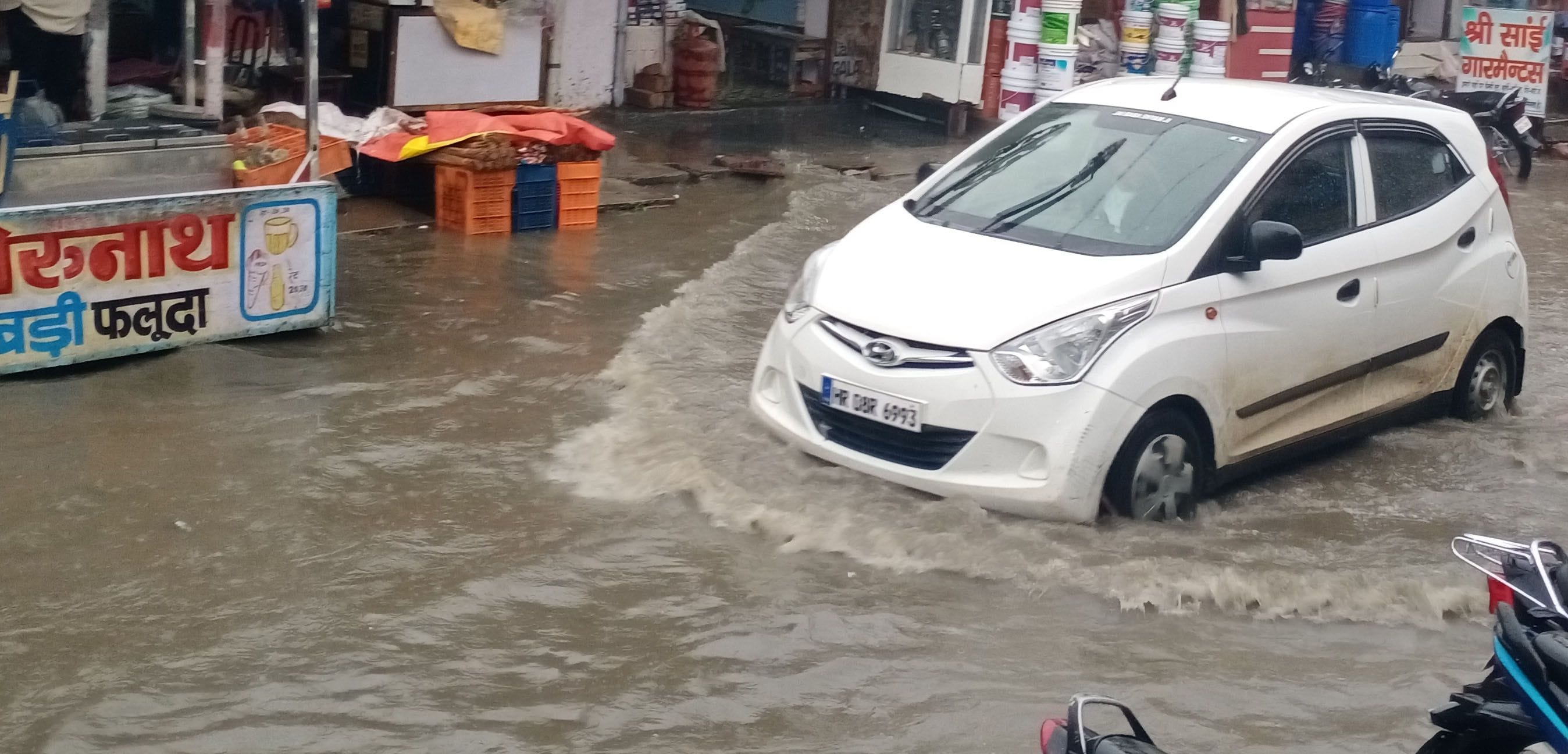  जुलाना के मेन बाजार में बरसात के कारण भरा पानी और उसके बीच से गुजरती कार।