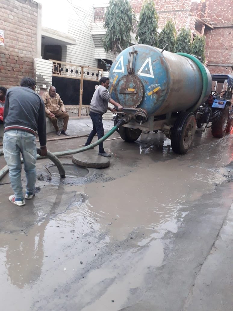 गली में टेंकर से सीवरेज की सफाई करते जनस्वास्थ्य विभाग के कर्मचारी। गली में टेंकर से सीवरेज की सफाई करते जनस्वास्थ्य विभाग के कर्मचारी।