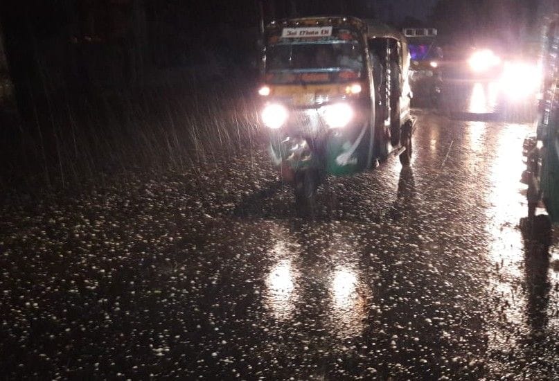हाथरस: बारिश व ओलावृष्टि के दौरान लाइट जलाकर जाते वाहन और सड़क पर पडे़ ओले।