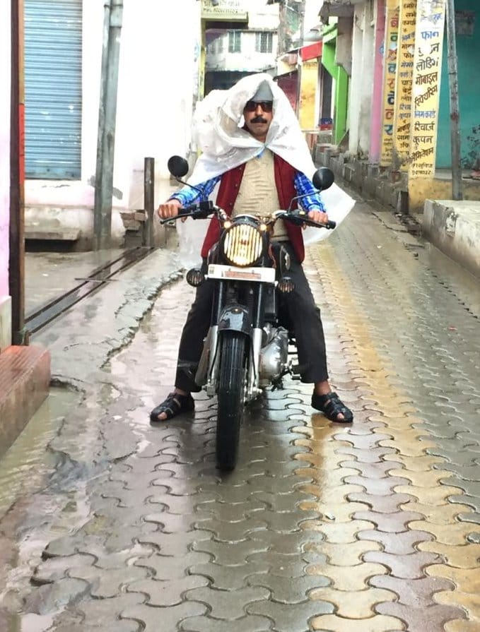 ऊन बरसात में पन्नी ओंढ कर जाता बाइक सवार