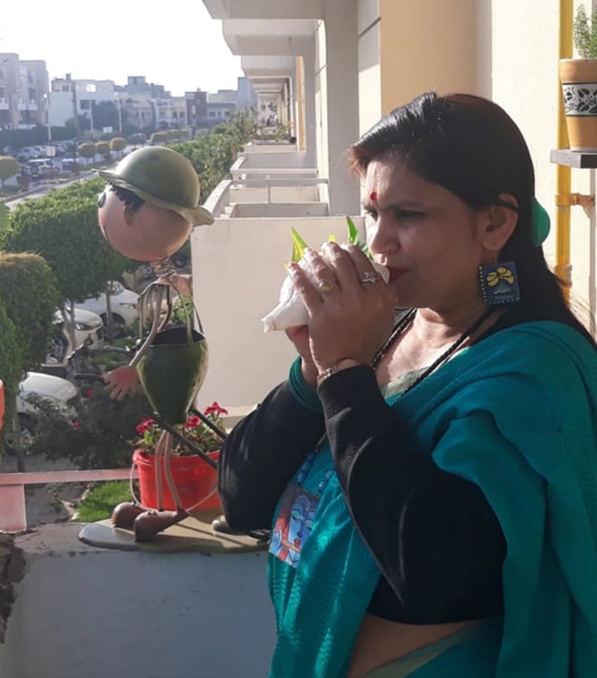 शहर की एक कालोनी में शंख बजाती महिला। शहर की एक कालोनी में शंख बजाती महिला।