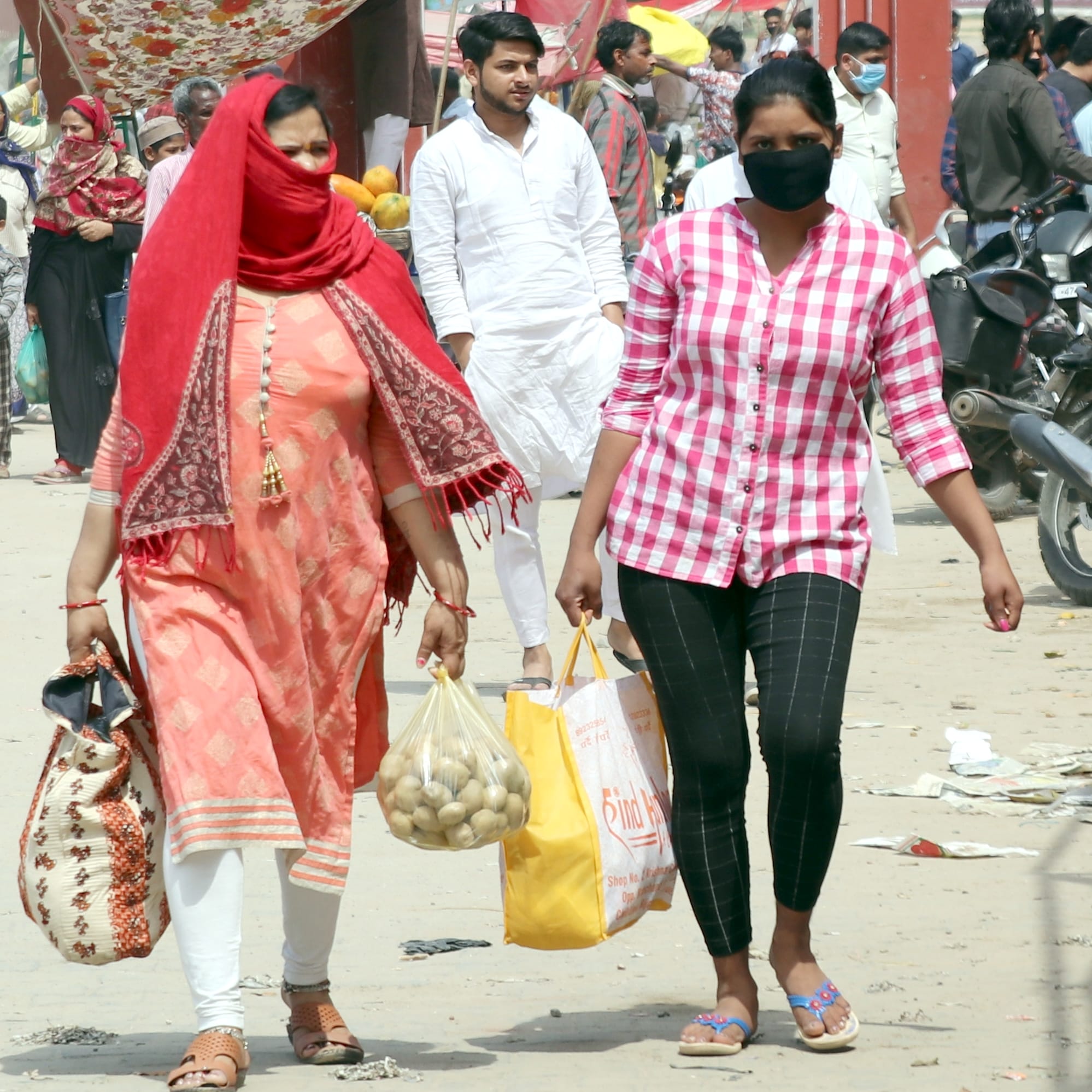बिजनौर में घरेलू सामान और सब्जी लेकर जाती महिला और युवती।