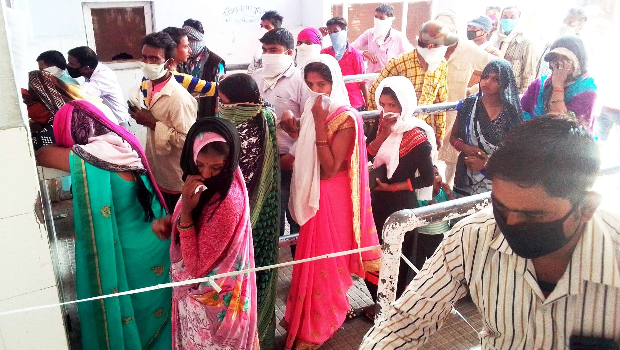 पर्चा बनवाने के लिए एक-दूसरे से सटकर खड़े लोग पर्चा बनवाने के लिए एक-दूसरे से सटकर खड़े लोग