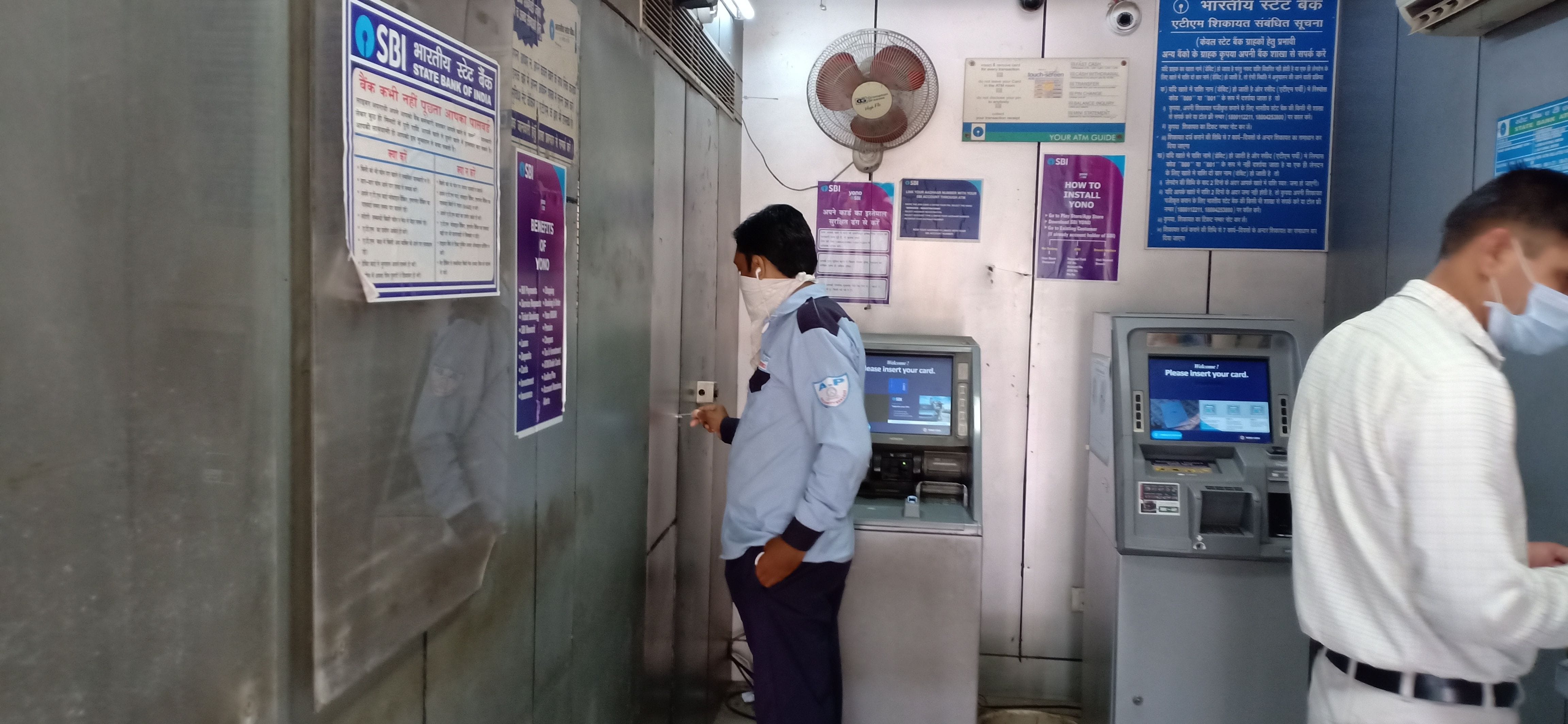एटीएम में बनी अलमारी का ताला खोलकर सेनिटाइजर निकालता सिक्योरिटी गार्ड। एटीएम में बनी अलमारी का ताला खोलकर सेनिटाइजर निकालता सिक्योरिटी गार्ड।